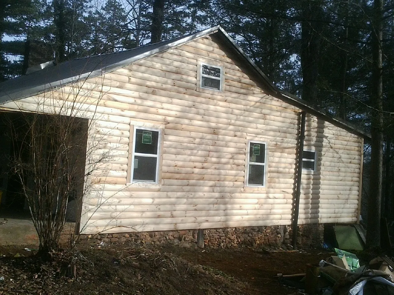 New log siding and dark metal roofing on a gable end in Algona