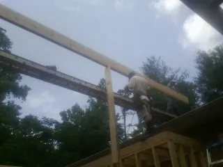 Carpenter setting a ridge beam over a new addition frame — Ice Dam Removal by Roofing Brothers in Algona