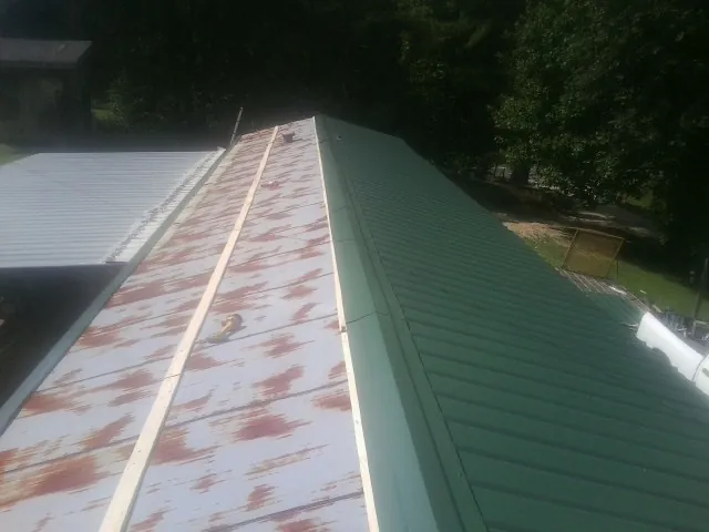 Old rusted panels beside newly installed green metal roofing — Wind Damage Roof Repair by Roofing Brothers in Algona