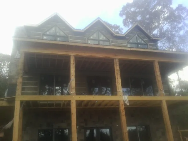 Dormers and porch framing on a large log home under construction — Roof Coating work by our crew in Algona
