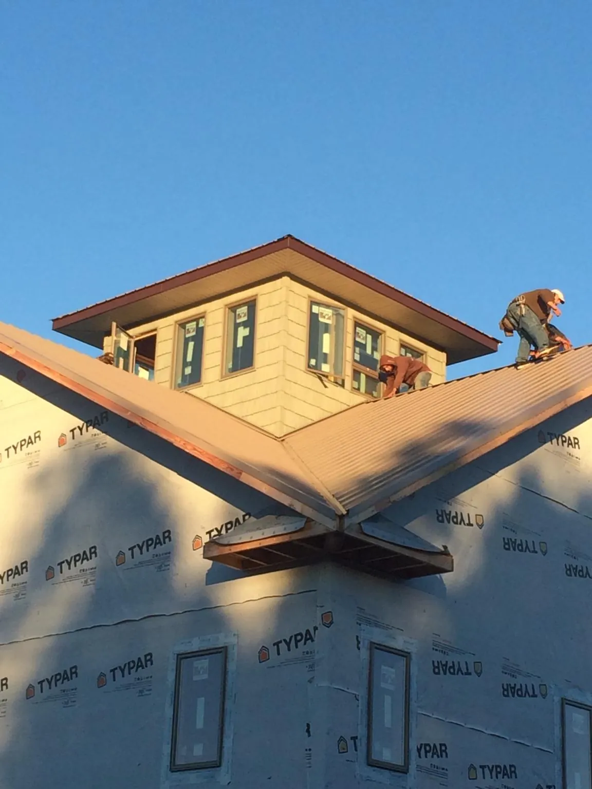 Roofers working around a rooftop cupola on a new metal roof at sunset — Roof Waterproofing in Algona by Roofing Brothers